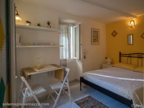 Camera luminosa giallo brillante al SoleMagia B&B Vernazzo con letto matrimoniale, scrivania, scaffali e accesso al balcone