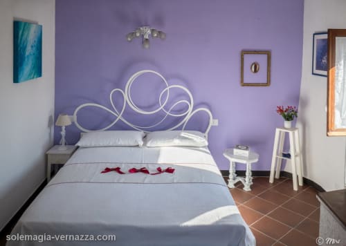 Camera da letto viola con testiera bianca ornamentale presso SoleMagia B&B a Vernazzo, Italia