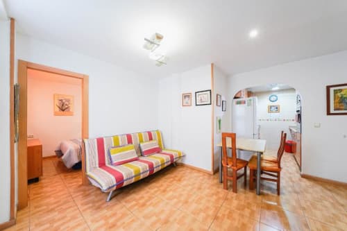 Área de estar de Casa Ferrer Barcelona con sofá colorido, muebles de madera y detalles en naranja en L'Hospitalet de Llobregat