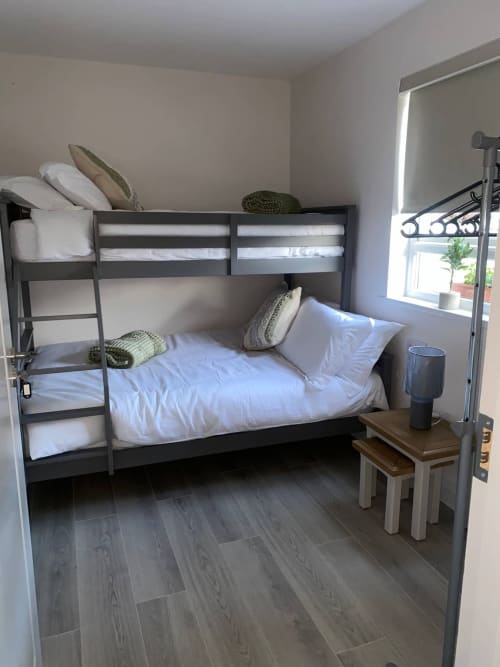Bunk bed setup at Duffy Lodge in Co Donegal with white bedding, wooden floor, and room-darkening blinds