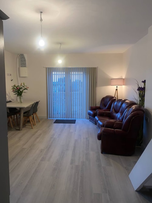 Modern apartment interior at Duffy Lodge, Co Donegal with burgundy leather sofa, dining table, and blue vertical blinds
