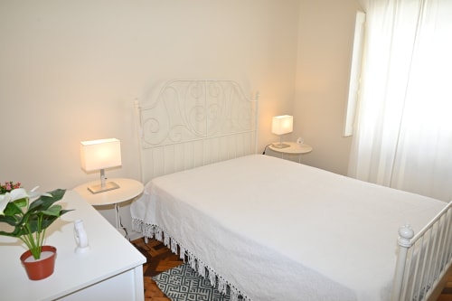 Chambre lumineuse à la Villa Sor avec lit à tête de lit en métal blanc, lampes de chevet et fenêtre à Ponte de Sor