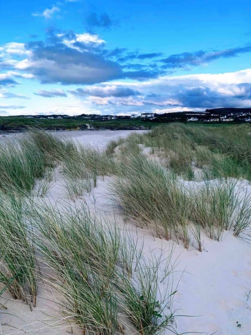 Sandy beach with marram grass overlooking Donegal estuary and coastal village at Duffy Lodge