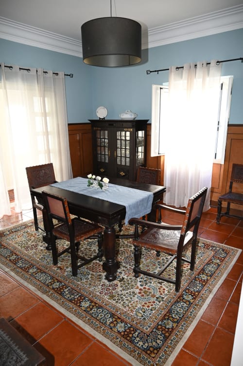 Elegante sala de jantar na Villa Sor com mesa preta, cadeiras de madeira, tapete decorativo e paredes azuis destacadas.