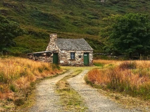 Historic stone cottage at Duffy Lodge in Co. Donegal with green doors surrounded by moorland