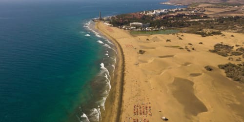 Vista aérea del complejo vacacional Villa Cacemar en Maspalomas con dunas de arena dorada, océano turquesa y playa organizada