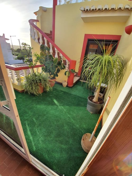 Colorful courtyard at Ocean View Lagos hostel with yellow walls, red trim, green artificial turf, potted plants, and