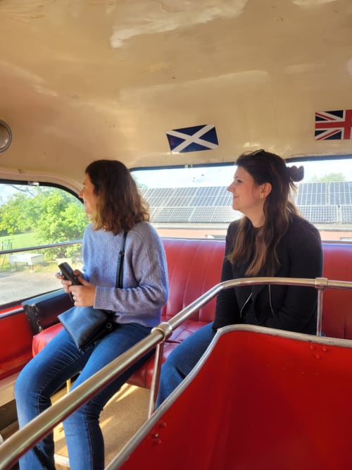 Twee vrouwen op het bovendek van een vintage open-top toeristenbus in Jalhay, België nabij Les Refuges Du Chalet
