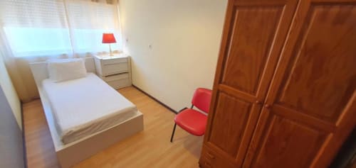 Quarto luminoso na Casa do Sol Algarve, Lagos com cama de solteiro, luminária vermelha, guarda-roupa em madeira e duas cadeiras vermelhas