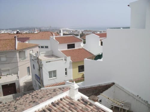 Vista aérea do hotel Casa do Sol Algarve em Lagos mostrando edifícios brancos com telhados de barro e a paisagem da cidade costeira