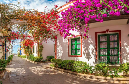 Encantador patio colonial en Villa Cacemar, Maspalomas con buganvillas vibrantes, contraventanas verdes y paredes encaladas
