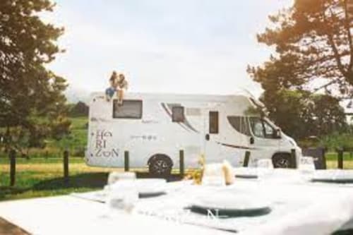 White motorhome with outdoor seating area surrounded by green trees at Esto si es vida property in Ribadesella