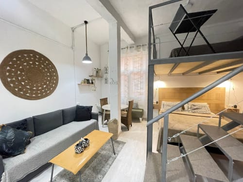 Moderno estudio en Huelintown Málaga con altillo, sofá gris y mobiliario contemporáneo