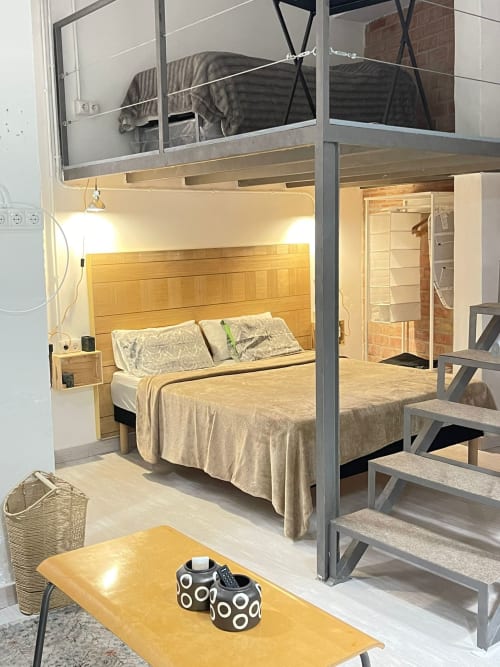 Moderno loft en Apartamentos Huelintown, Málaga, con dormitorio en altillo, cama de madera y sala luminosa