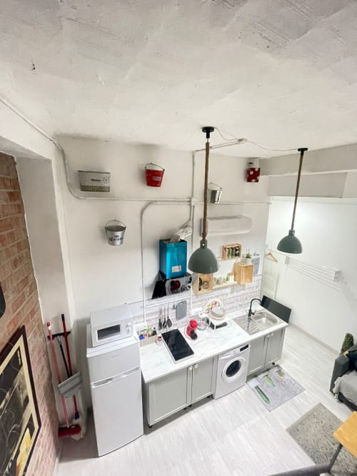 Cocina moderna y compacta en Apartamentos Huelintown, Málaga con electrodomésticos blancos, iluminación colgante y mostrador organizado