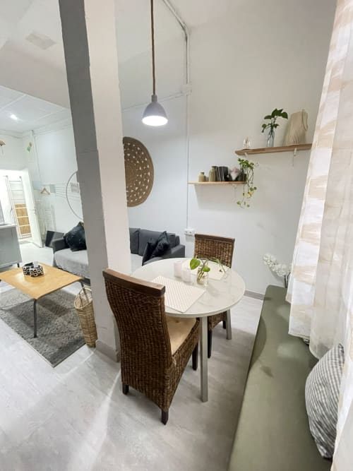 Espacioso apartamento moderno en Apartamentos Huelintown, Málaga, con mesa redonda de comedor, sillas tejidas y diseño contemporáneo