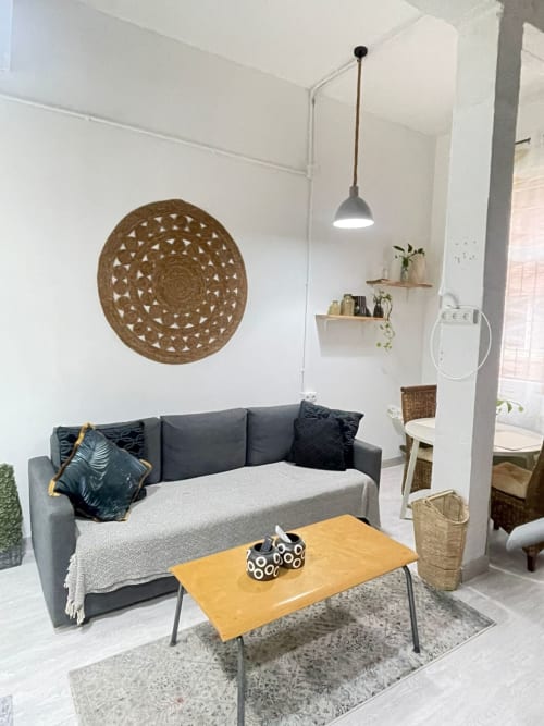Sala moderna de apartamento en Málaga con sofá gris, arte mural de madera, mesa de café amarilla e iluminación colgante en Huelintown