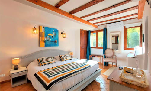 Chambre lumineuse à La Bergerie Du Moulin B&B à Taradeau avec poutres en bois, literie rayée et accents en terre cuite