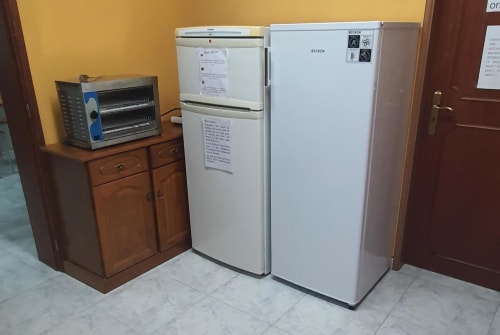 Cozinha do albergue Sunny House em Lagos com geladeiras Becken brancas e forno torradeira sobre armário de madeira