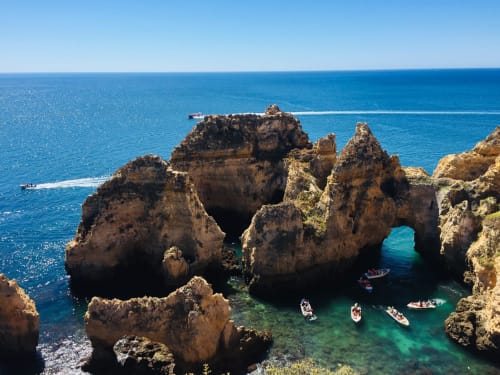 Formações rochosas douradas dramáticas e águas turquesas em Ponta da Piedade, Lagos Portugal com barcos abaixo