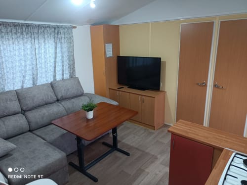 Living room in Bungalow A at Buda Beach hotel, Chipiona, with gray sofa, TV, coffee table and garden views