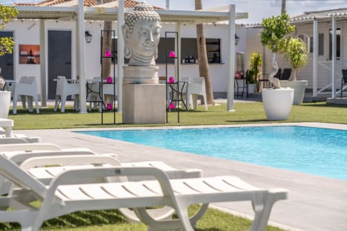 Bungalow Buda Beach pool area in Chipiona with lounge chairs, Buddha statue, white bungalows and garden view