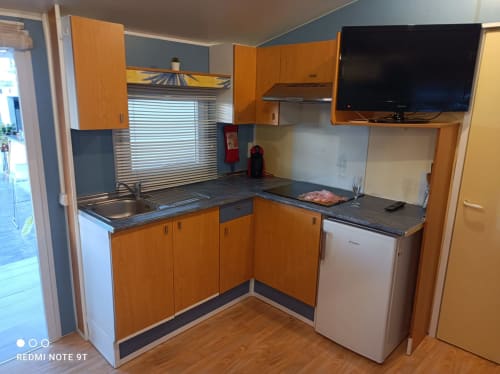 Modern kitchen in Bungalow Buda Beach, Chipiona with orange cabinets, dark countertops, and flat-screen TV