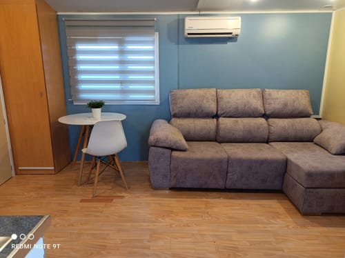 Modern living room in Bungalow I at Buda Beach hotel, Chipiona, with gray sofa, white table, and blue walls