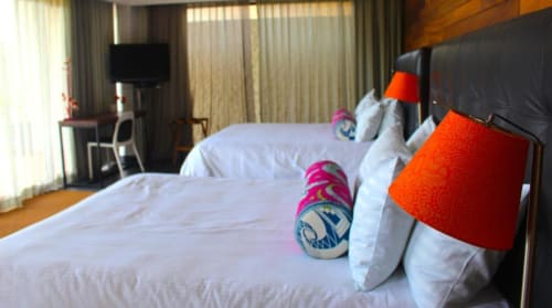 Modernes Zimmer des Isla Tajín Beach & River Resort in Tuxpan mit Einzelbetten, roten Akzentleuchten und Seeblick