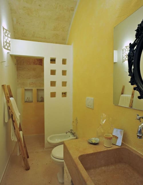 Bagno giallo luminoso presso il Masseria Picca Picca B&B con vasca in terracotta, lavandino e arredi rustici a Morciano di Leuca