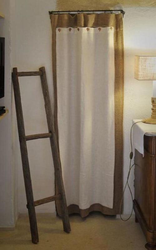 Bagno rustico della Masseria Picca Picca con tenda doccia color crema e oro, scaffale in legno a forma di scala, e arredamento vintage