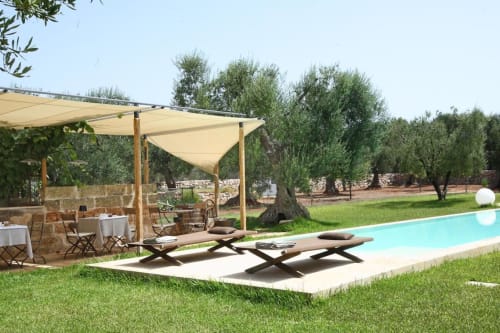 Area piscina di Masseria Picca Picca con pergolato color crema, lettini e uliveto a Morciano di Leuca