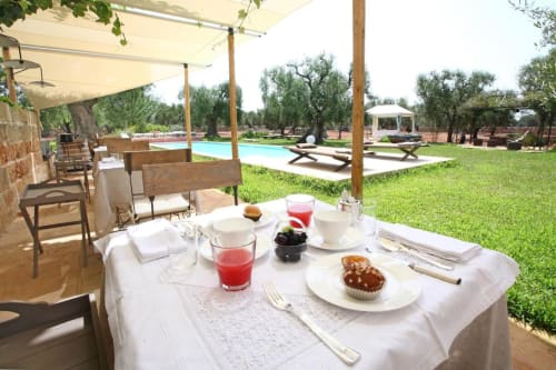 Tavolo della colazione a Masseria Picca Picca B&B a Morciano di Leuca con pasticcini, succhi e vista sul giardino piscina