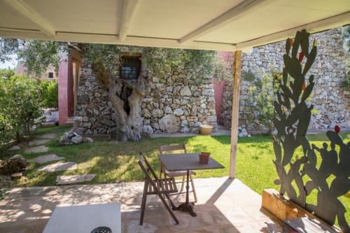 Patio ombreggiato della Masseria Picca Picca B&B a Morciano di Leuca con tavolo, sedie, cactus e edificio in pietra