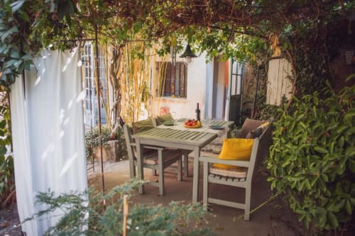 Charming courtyard patio at Ancienne Maison des Gardes in Lourmarin with dining table, lush vines, and Mediterranean-style