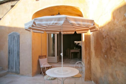 Shaded terrace with striped umbrella and outdoor seating at Ancienne Maison des Gardes, Lourmarin