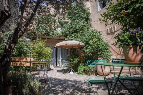 Jardin de cour verdoyant à l'Ancienne Maison des Gardes de Lourmarin avec mobilier vert et parasol