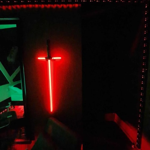 Croix néon rouge illuminant l'intérieur sombre de l'hôtel Les Deux Porches à Verrières, France