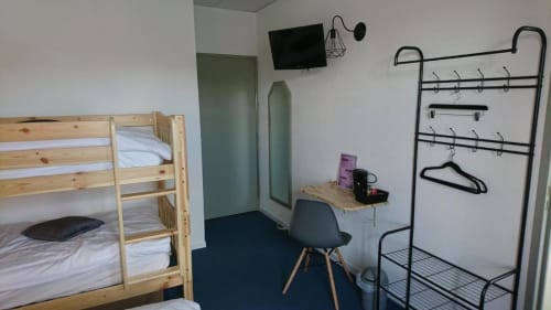 Chambre économique aux Deux Porches avec lits superposés, bureau, chaise, portant et TV murale à Verrières