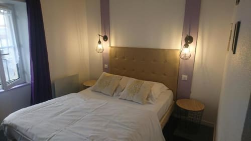Chambre moderne de l'hôtel Les Deux Porches à Verrières avec lit queen-size, tête de lit en laiton, luminaires suspendus et vue sur les jardins