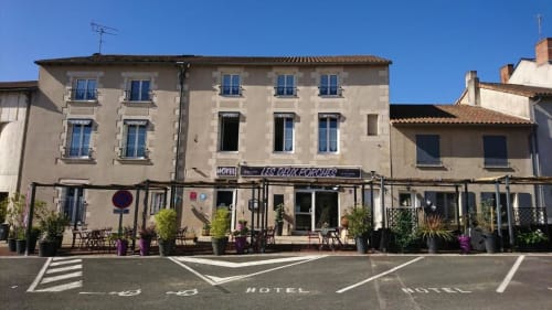 Hôtel Les Deux Porches à Verrières, France - bâtiment beige aux fenêtres bleues et terrasse de rue