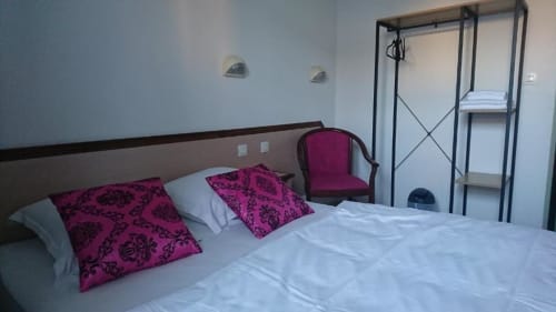 Chambre lumineuse de l'hôtel Les Deux Porches à Verrières avec literie blanche, oreillers magenta et mobilier moderne