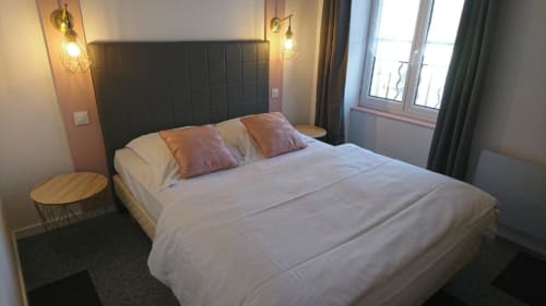 Chambre moderne de l'hôtel Les Deux Porches à Verrières avec lit queen-size, tête de lit noire, luminaires suspendus et grandes fenêtres