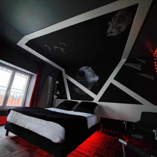 Chambre thématique Star Wars aux Deux Porches avec fresque Étoile de la mort au plafond, lit noir aux oreillers blancs et ambiance rouge