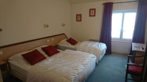 Chambre d'hôtel aux Deux Porches avec deux lits, coussins rouges et fenêtres aux rideaux violets à Verrières