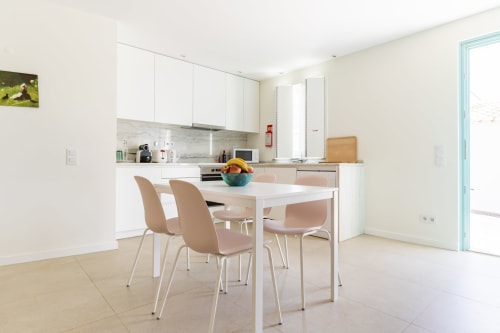 Cozinha e área de refeições modernas na villa Casa Hortas, Bordeira, com armários brancos, mesa de jantar e cadeiras bege