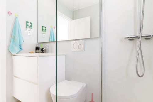 Banheiro moderno na villa Casa Hortas com pia branca, espelho, sanitário e box de vidro no Star Host Bordeira