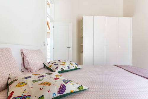 Quarto luminoso na villa Casa Hortas em Bordeira com duas camas, almofadas coloridas com padrão de guarda-chuva, roupa de cama rosa e branca