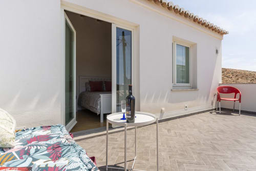 Terraço da villa Casa Hortas em Bordeira com acesso ao quarto, mesa branca, garrafa de vinho e vista para a montanha