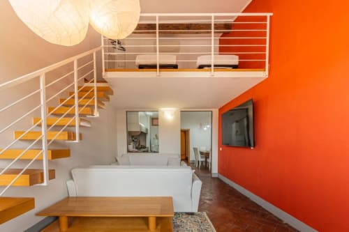 Loft moderno a Firenze con scala bianca, parete rossa, mezzanino e arredi contemporanei